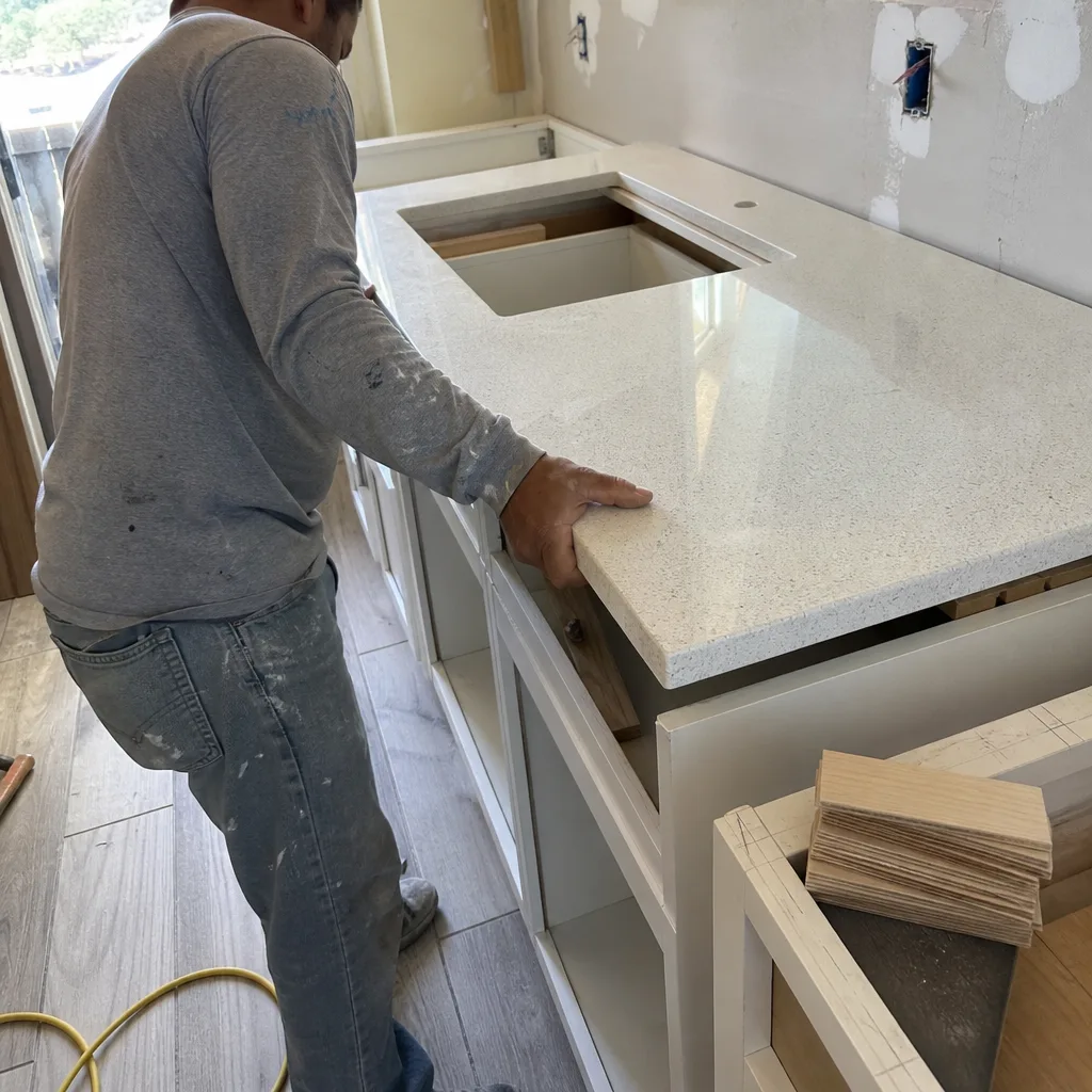 Contractor installing a white quartz countertop in a kitchen remodeling project